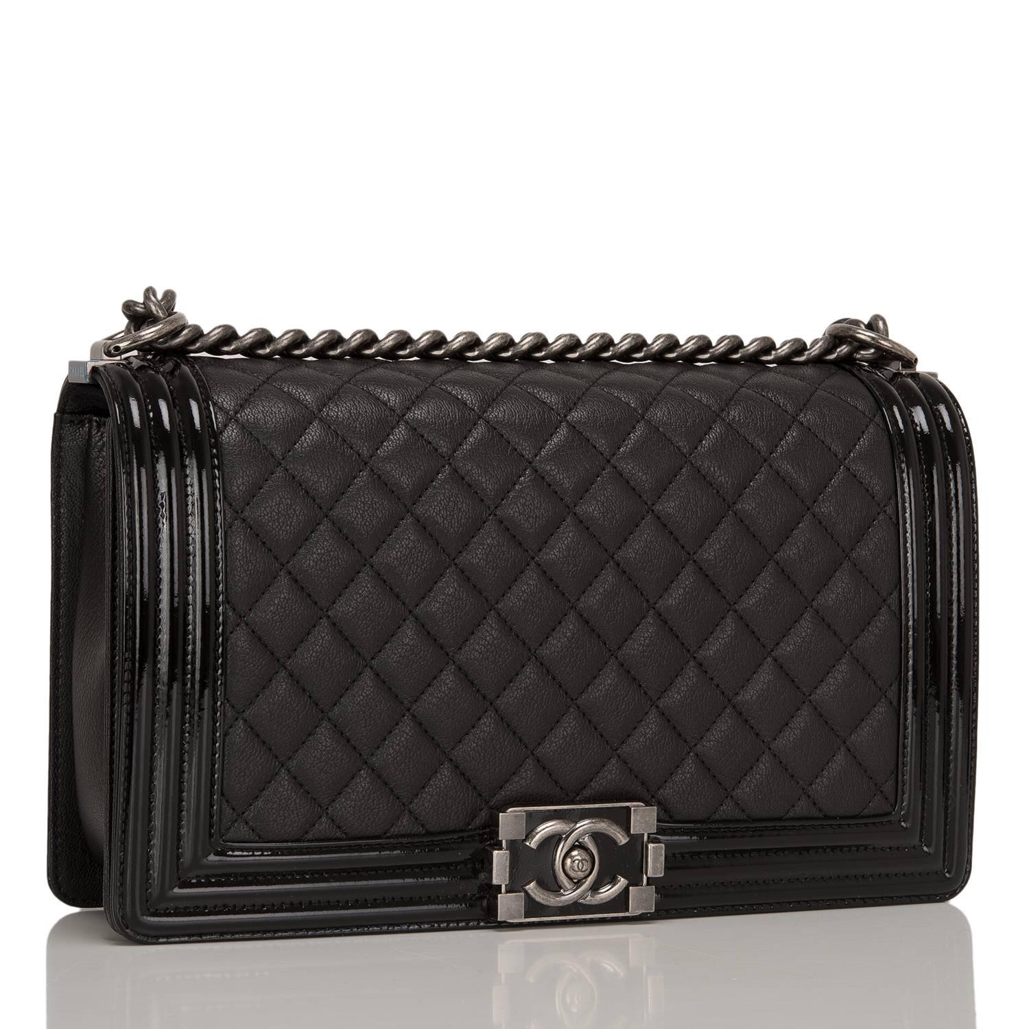 This Chanel New Medium Boy bag is made of black goatskin leather and accented with patent leather trim and aged ruthenium hardware.

The bag features a full front flap with a unique CC logo closure in a glossy lacquer, patent leather trim edging