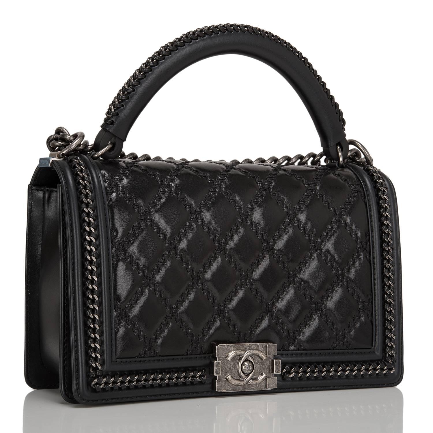 This Chanel New Medium Boy bag with a top handle is made of shiny goatskin leather and accented with aged ruthenium hardware.

The bag features a limited edition braided leather and chain top handle, a full front flap with the Boy signature CC