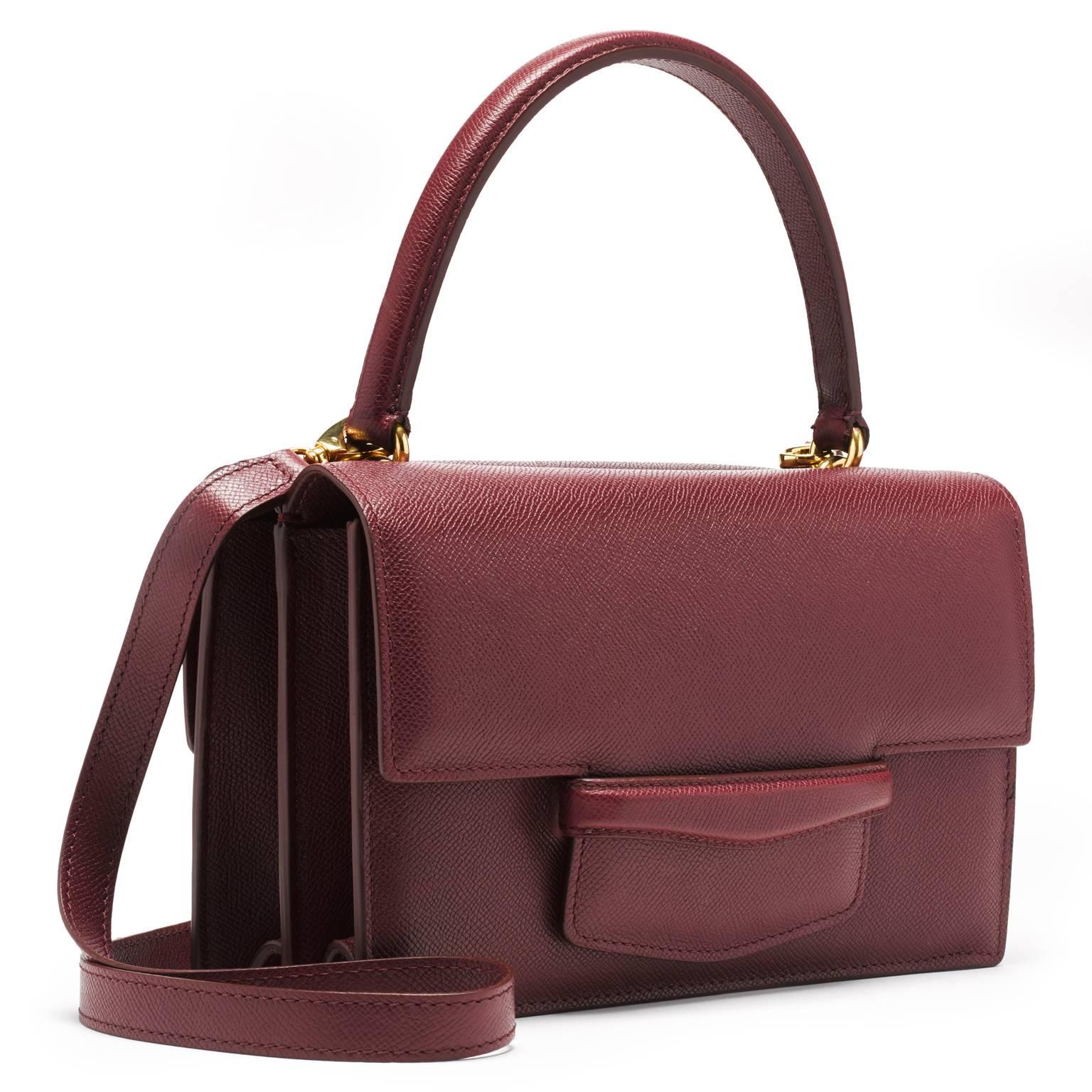 This double gusseted bag is made of pebbled leather in a matte finish. The interior is lined in brown suede. A stitched double-sided handle is joined to the bag with two interlocking gold rings. There is an additional 40” detachable shoulder strap.