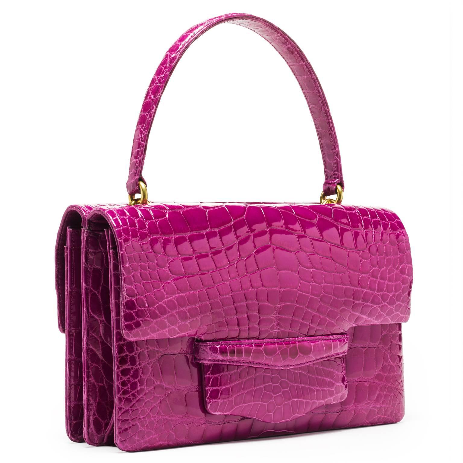 This double gusseted alligator bag is fully lined in leather. A stitched doubled sided handle is joined to the bag with interlocking gold rings. 

- one exterior pocket in center of the bag 
- four interior pockets 
- handle rises 6