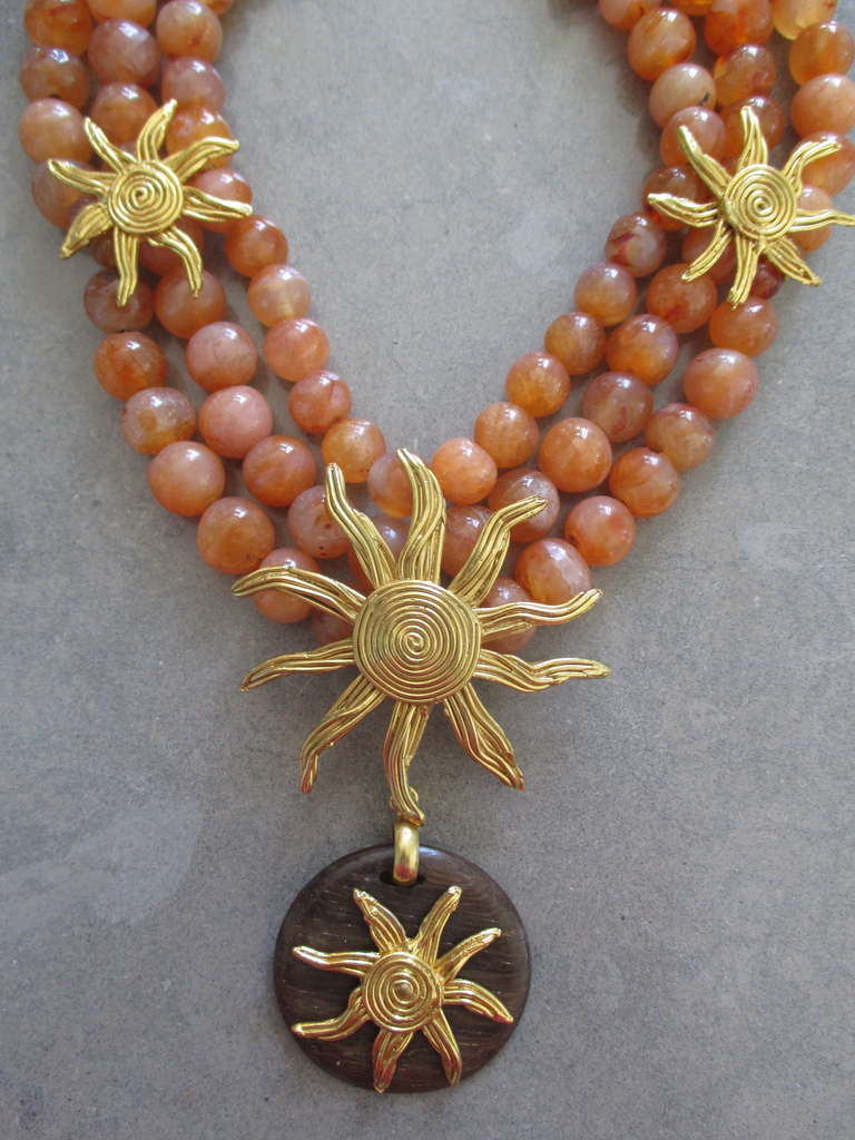 Yves Saint Laurent Bold Carnelian and Wood Necklace ,
Three rows of carnelian beads accented with gold sunbursts with a wooden pendant drop.
Made in France.