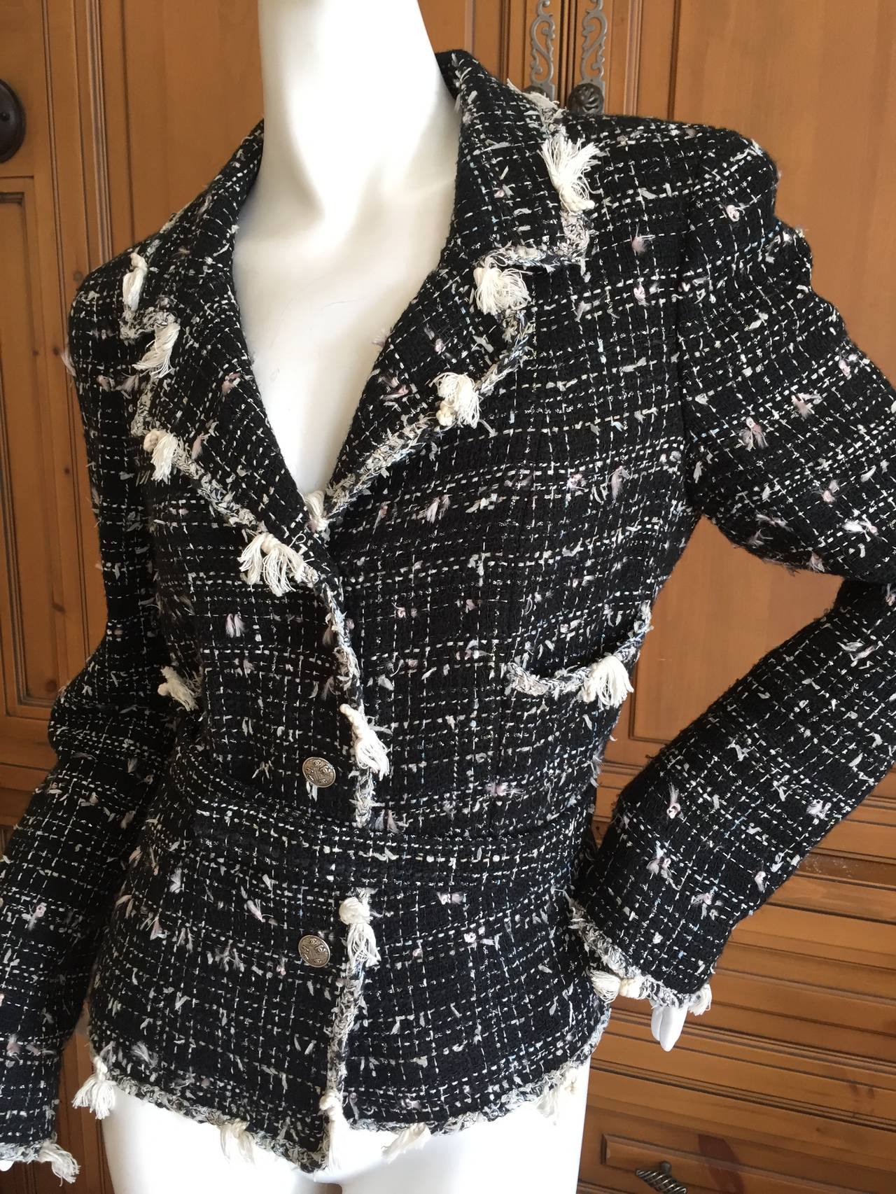 Classic Black Belted Jacket from Chanel.
2005 Cruise 
Size 42
Beautiful black and ivory fantasy tweed with fringed details.
Lined in luxurious camelia patterned silk with a chain weighted hem.
Silver buttons including 3 on each cuff.
The