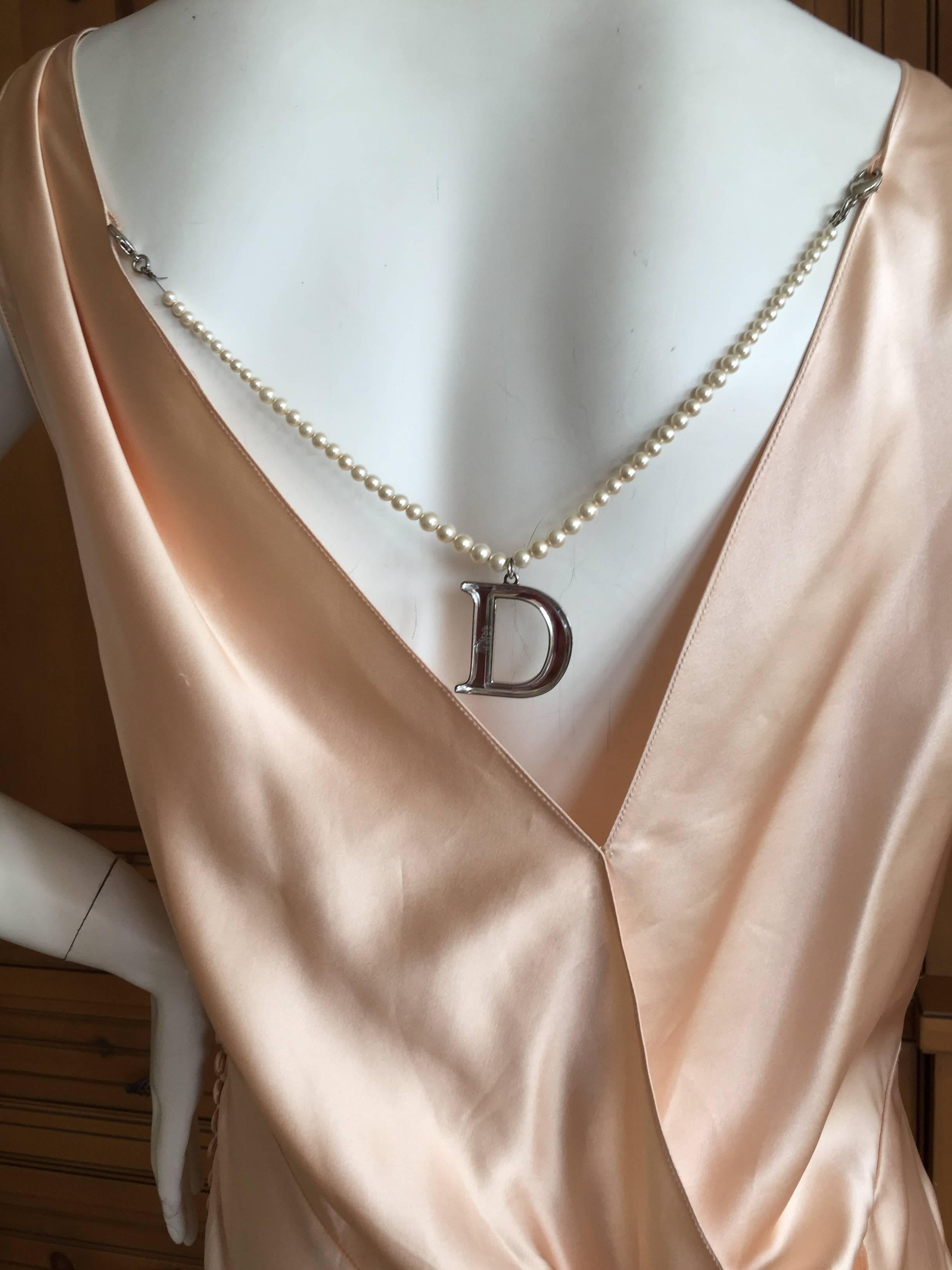 Maravilloso vestido de noche de corte al bies con un detalle de perlas desmontable de Christian Dior by John Galliano.
La espalda escotada y drapeada deja ver un pequeño collar de perlas con un gran colgante D de plexiglás.
Talla 44 difícil de