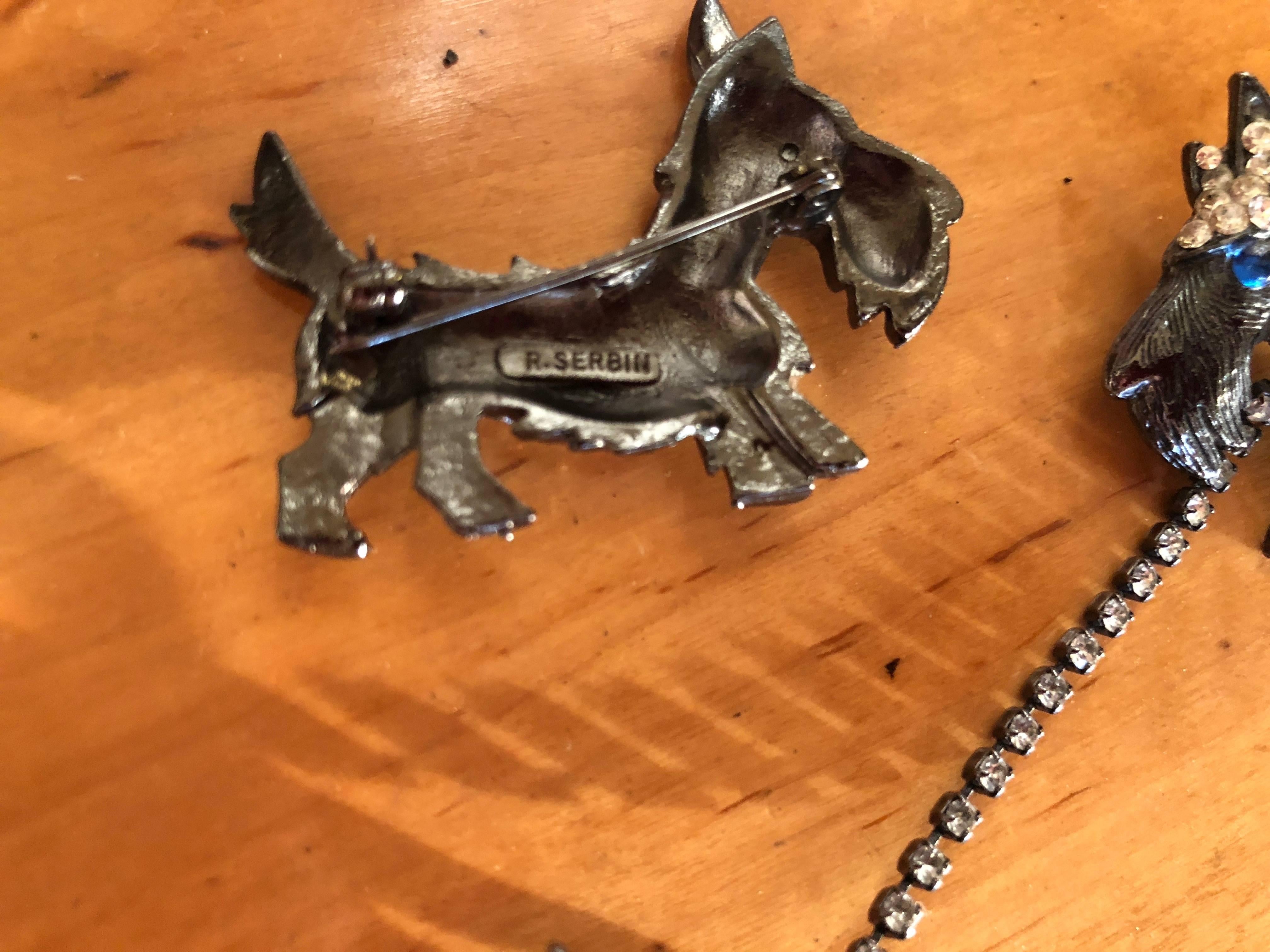 Scotty dog pins in gunmetal and crystal by R.  Serbin 1983.
Two doggies are attached by a rhinestone leash, while the other walsk solo.