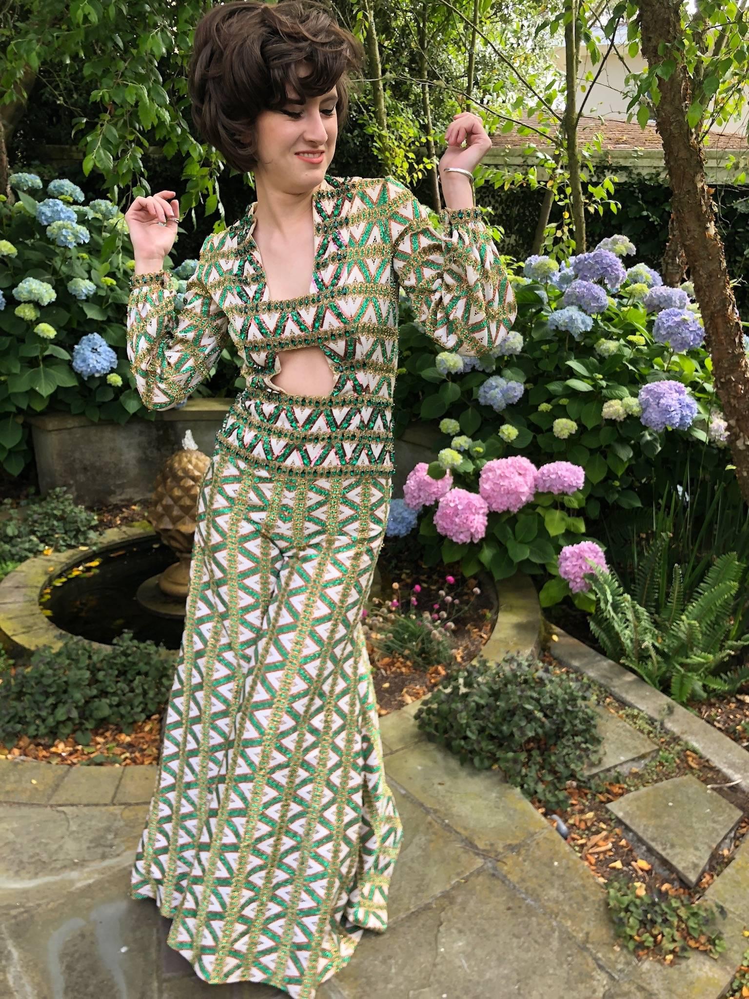 Cardinali Trelliage Pattern Key Hole Jumpsuit with astonishing Emerald Crystals.
The crystals are huge.
Wild wide leg jumpsuit in a trellis pattern with really large emerald crystals framing the key hole bust.
Circa 1970, this was the showroom