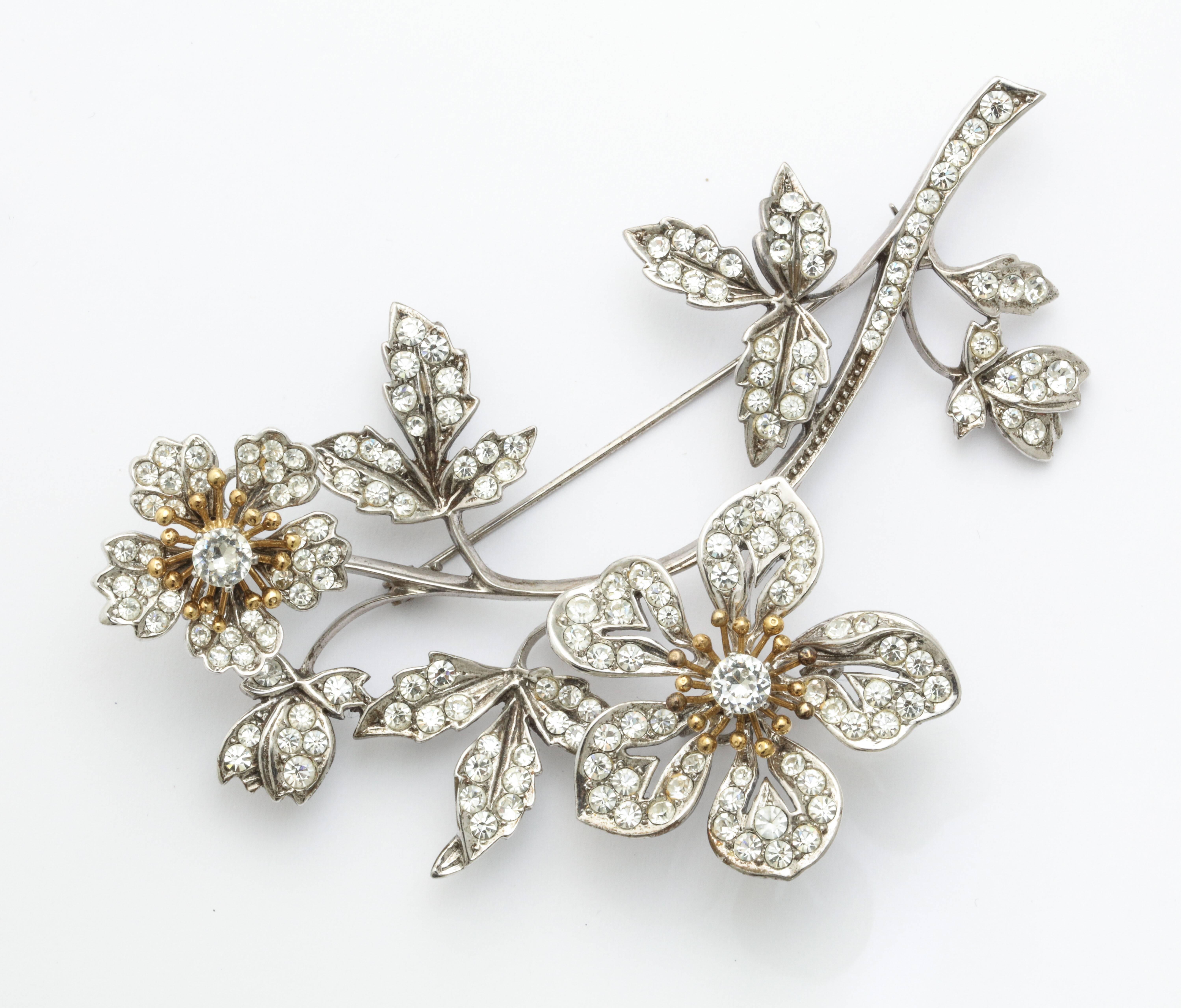 A shimmering floral tremblant pin marked 925 and designers stamp with moving flower crystals on finely crafted silver stem. With matching clip earrings. 