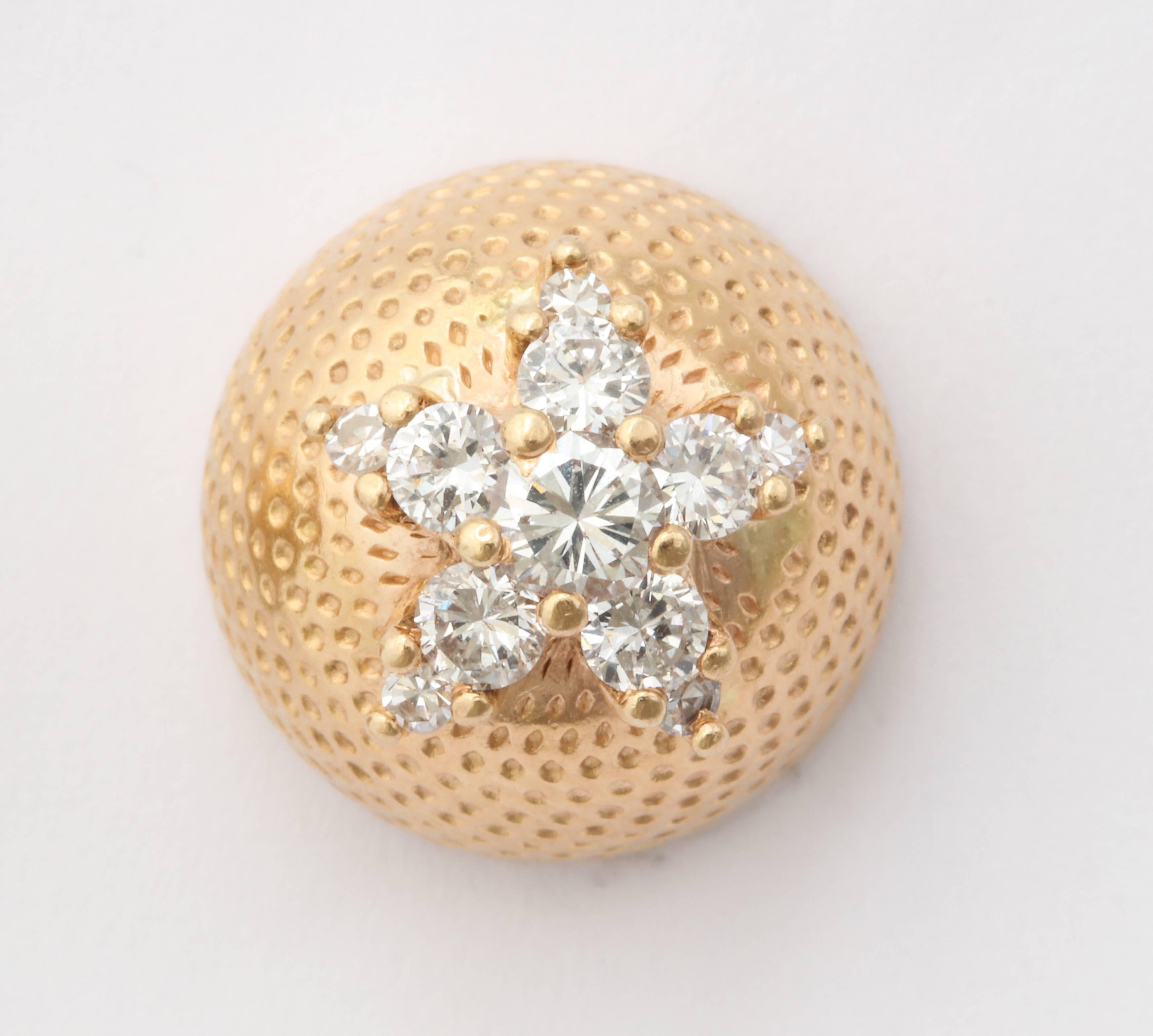 A beautiful pair of stud earrings with a group of diamonds arranged as a floral cluster on a button of stippled 18 kt gold