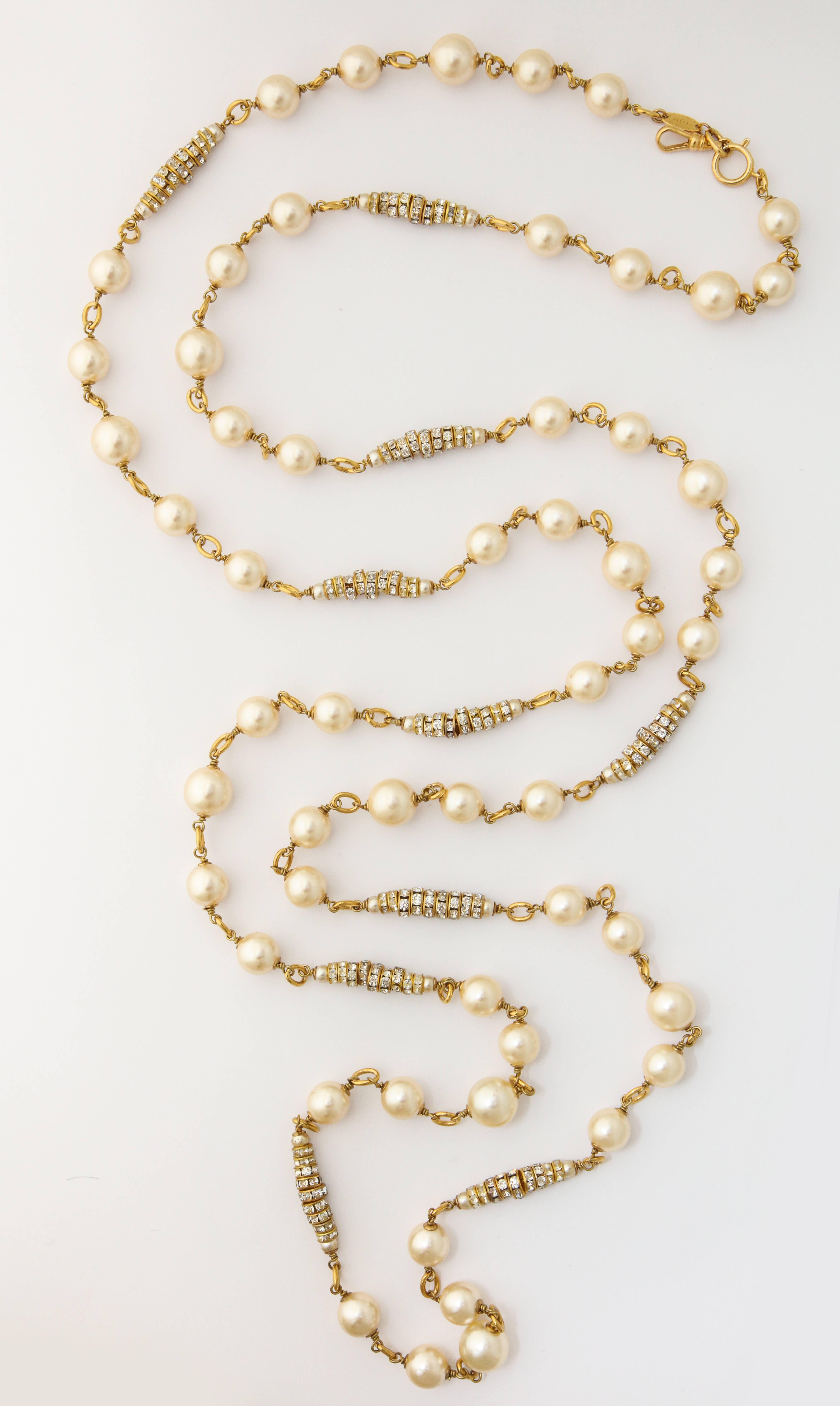 A wonderful long necklace by Chanel with faux natural pearls on a long chain with several rhinestone clusters. It can be worn doubled and triple up.