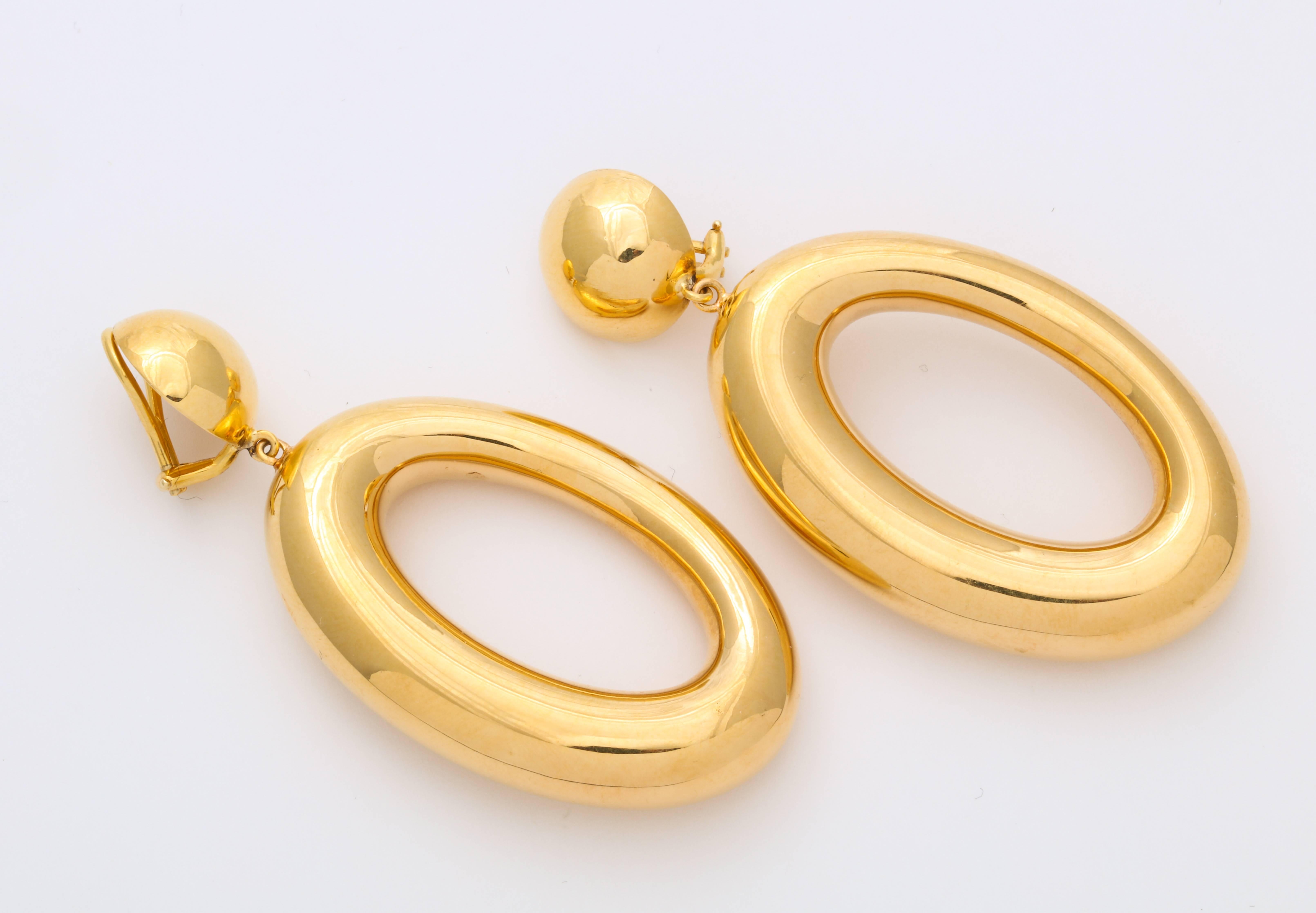 A stylish pair of Italian 18 kt gold earrings with gold tabs and asymmetric hoops dangle from them. Market with Italian and gold mark. 