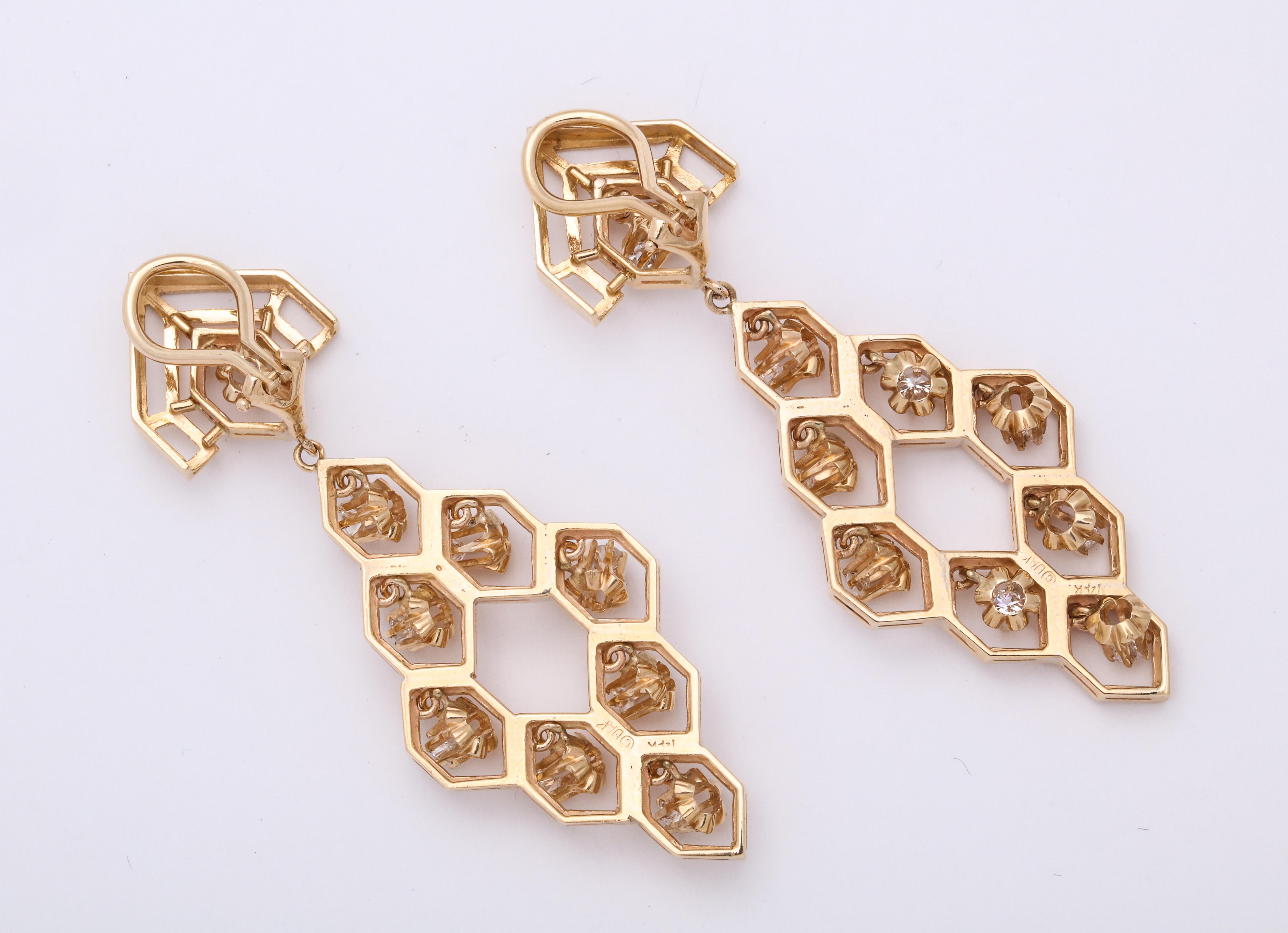 A pair of flirtatious dangle earrings in 14 kt gold in a honeycomb form. Free floating  diamond in a floral form  dangle from the center of the 18 hexagons.  