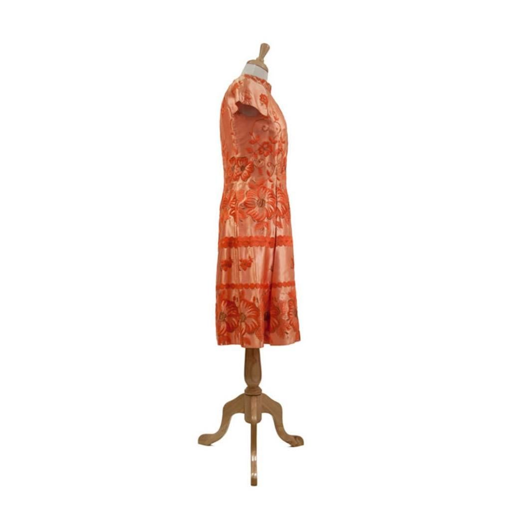 Fabulous apricot rayon satin embroidered cocktail dress.
Princess Line with pleats from  hip line at front, Cap sleeves, Band collar (stand up collar) with back hook and eye closure. Long back zipper, fully lined.
The design of the dress takes full