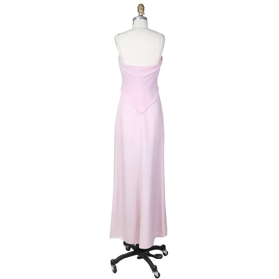 This floor length gown is made from a light pink silk chiffon.  A delicate fabric drape begins at the center of the bust in a point and continues down and around the back where it ends in a point to make a V shape.  