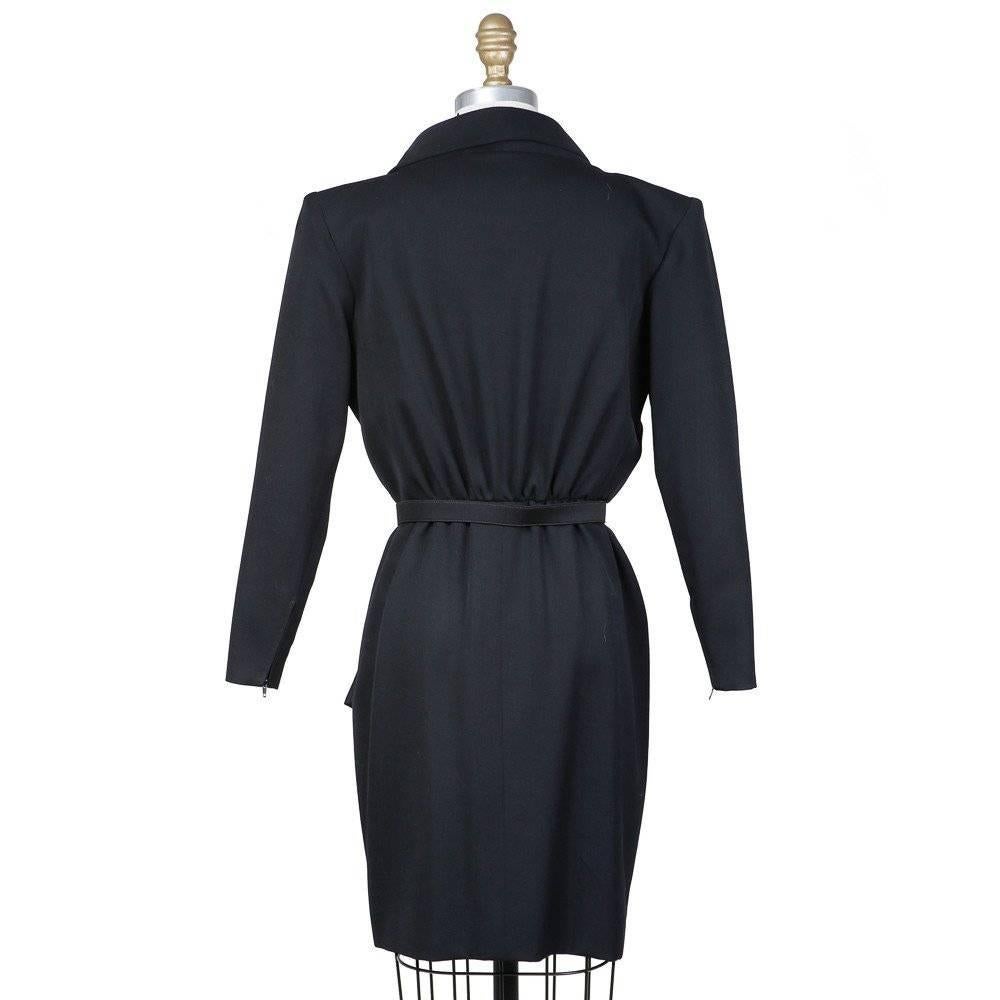 This is a black dress by Yves Saint Laurent circa 1980s.  It has lapels and is reminiscent of a tuxedo jacket.  It includes a belt and shoulder pads and features 3/4 sleeves.  The closures are 3 snaps on waist, with hook-and-eyes both under and at