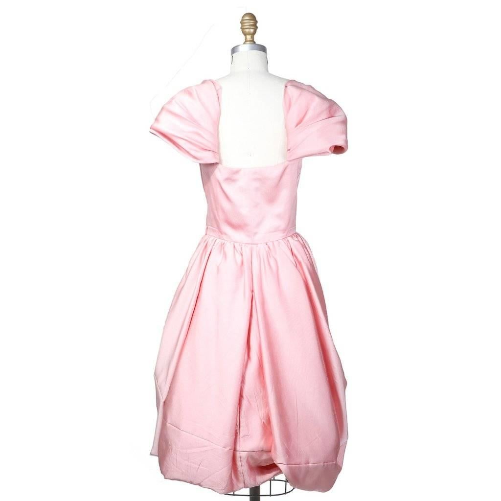 This is a short princess dress from Yves Saint Laurent c. 1980s.  It is made from 100% silk in a bubble gum pink color.  It features cap sleeves and curved seams to create a bubble skirt effect.  The closures include internal waist hook-and-eye,