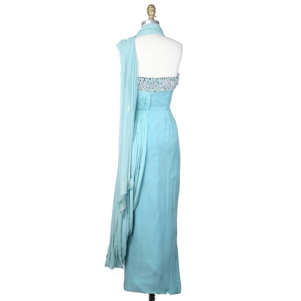 This is a gown by Madame Grès c. late 1950s.  The upper part of the bodice is embellished with looped beads and sequins in a white/green/baby blue color scheme.  Half of the lower part of bodice is micro pleated, which then transitions into the