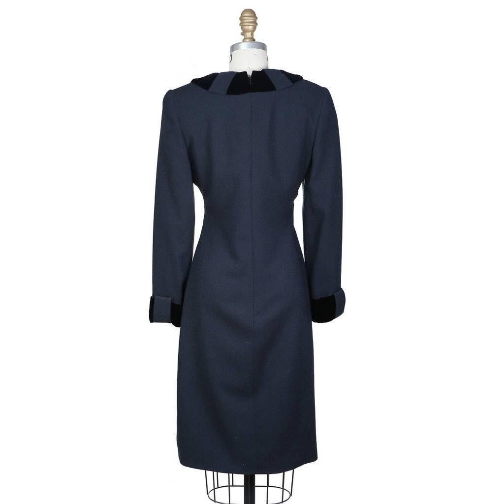 This is an early Carolina Herrera dress c. 1980s.  It's a dark gray-blue wool and polyester blend that features wide black velvet trim that loops around the cuffs and the neckline. The closure is an invisible zipper down the back with hook and eyes
