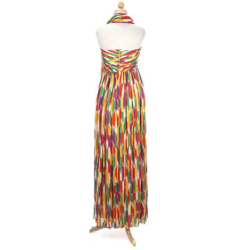 This is a strapless floor length dress by Givenchy Nouvelle Boutique circa 1970s.  It is made from silk with an colorful abstract print and features two drapes over the bust with a hanging tie in the middle. It has a yellow silk slip lining,