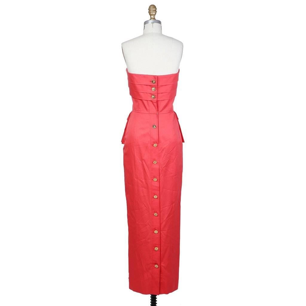 This is a red strapless dress by Chanel c. 1980s. It features horizontally layered strips over the neckline and two pleated hip pockets that double as a peplum and are functional.  The dress closes down the back with gold buttons that have a Chanel