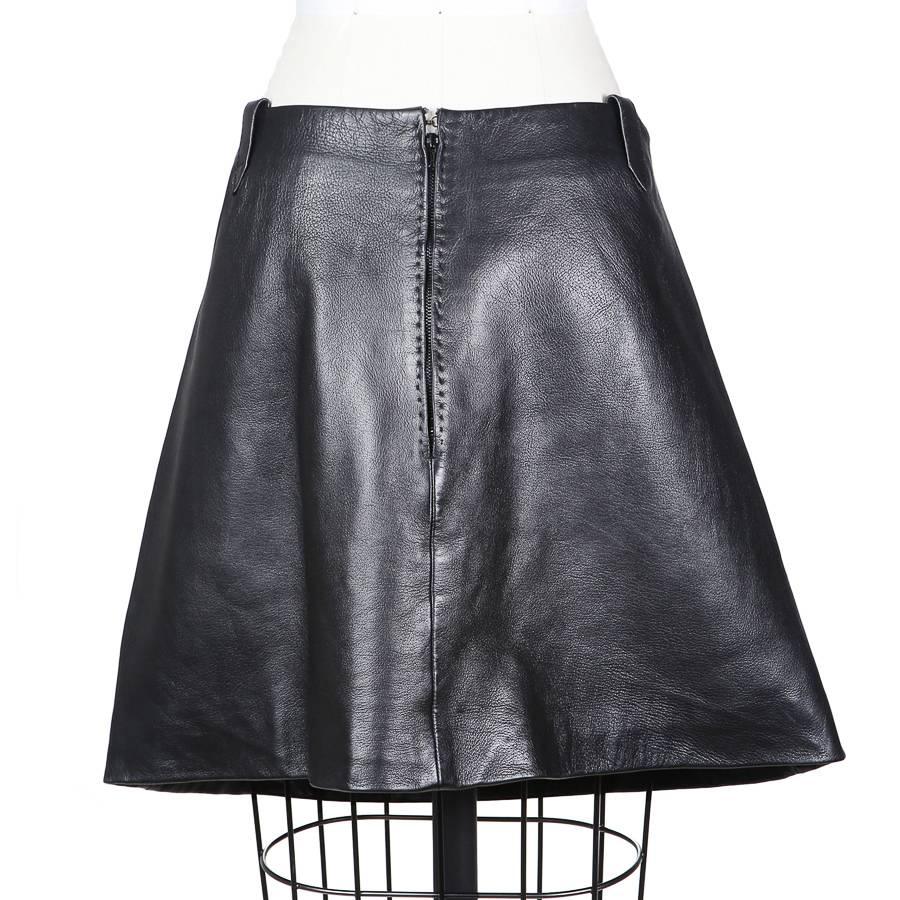 This is a black leather A-line skirt by Pierre Cardin c. 1960s.  It features a set of five red leather geometric “0” shapes.  The skirt also includes four belt loops, two in front and two in back.  It is also satin lined and the closure is a back
