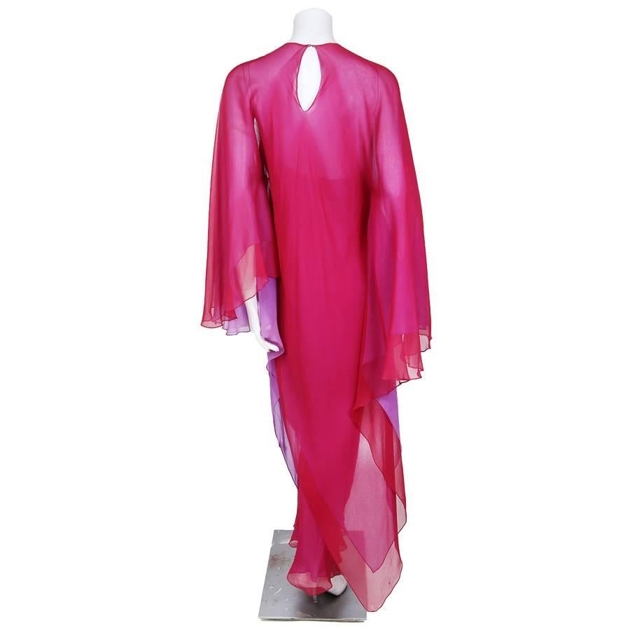 This is a double layer chiffon dress by Halston c. 1970s.  It’s a two part dress; the first is the slip and the second is the matching poncho.  The slip has spaghetti straps and two chiffon layers, lavender underneath and fuchsia on top.  The poncho