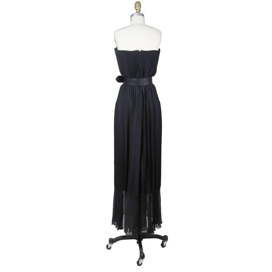 This is a black strapless dress made from virgin wool by Jean Paul Gaultier c. 1990s.  It features accordion pleats all around and includes a black leather belt to cinch the waist.  The inner boustier is structured, satin lined, and includes a