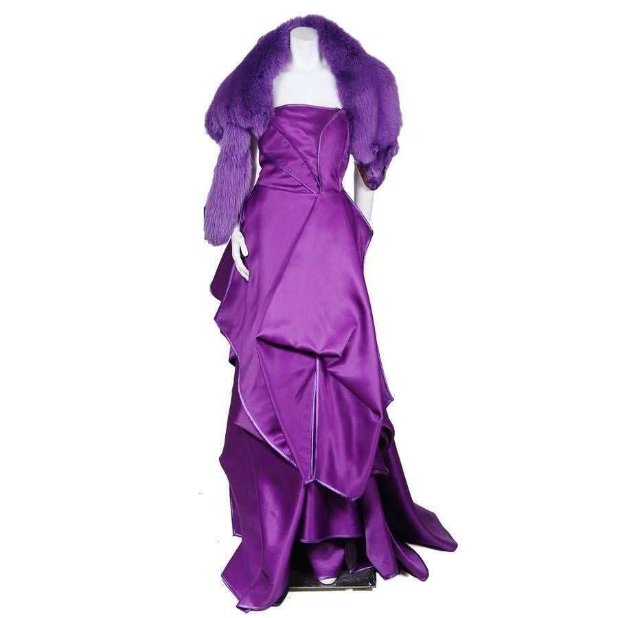 This is a strapless gown by Christian Lacroix c. 1980s.  It features origami draped and folded fabric to create depth and dimension around the dress.  The edges of the draped fabrics are piped in a different toned purple.  Styled with a purple fox