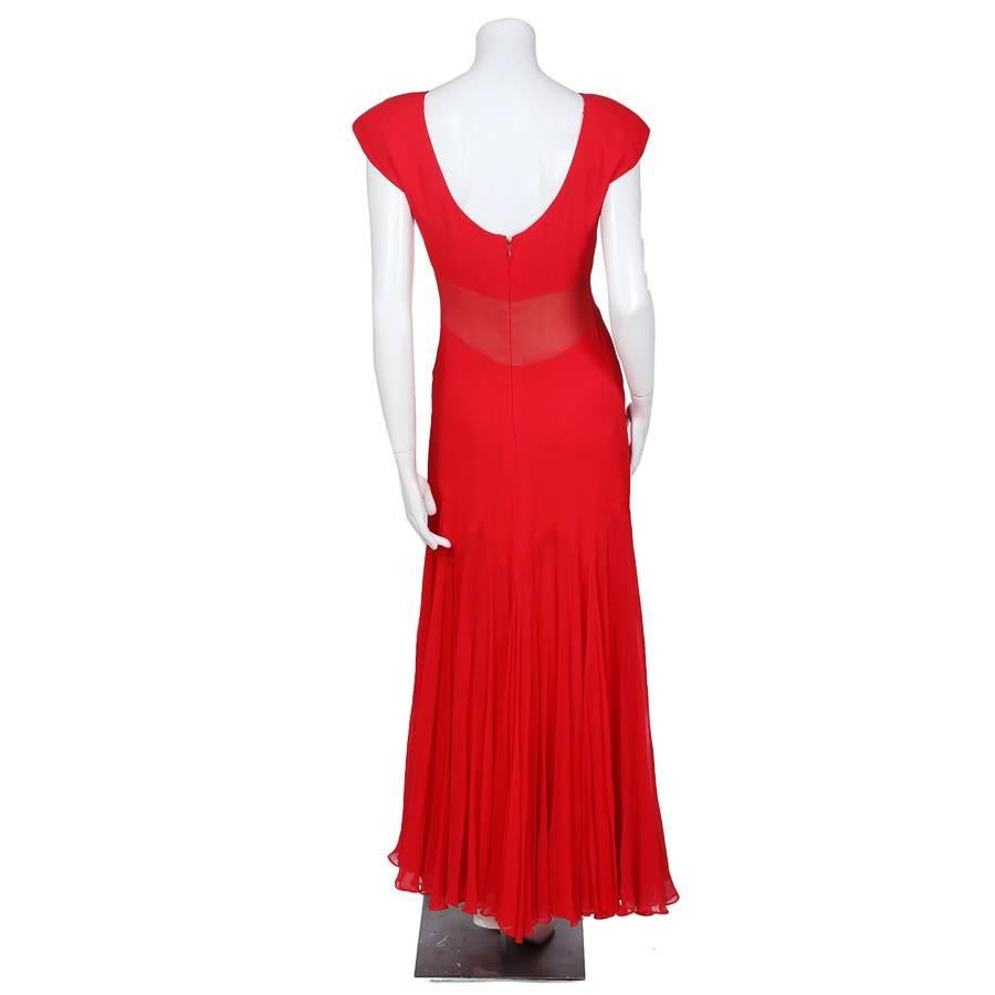 This is a red chiffon dress by Scaasi c. 1980s.  It features a drop waist using a horizontal zig zag seam.  It is made from multiple layers of chiffon, with a nude chiffon below the bust to give the illusion of a sheer panel.  The closure is a