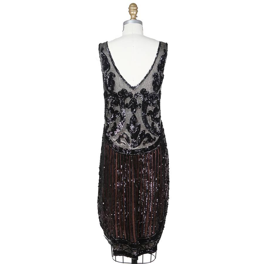 This is a fine mesh dress ornamented with beads and sequins c. 1920s/1930s.  The designer is unknown due to it’s age and lack of tags.  The top is made from a black mesh that features a background of beaded vertical stripes with a baroque motif