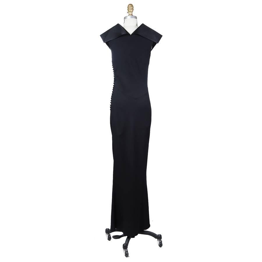 This is a black dress by Christian Dior c. late 1990s/early 2000s.  It features a stiff ridged sailor style collar that bends and folds over the shoulder.  The closures are a row of buttons with loops down the side. Made in France.