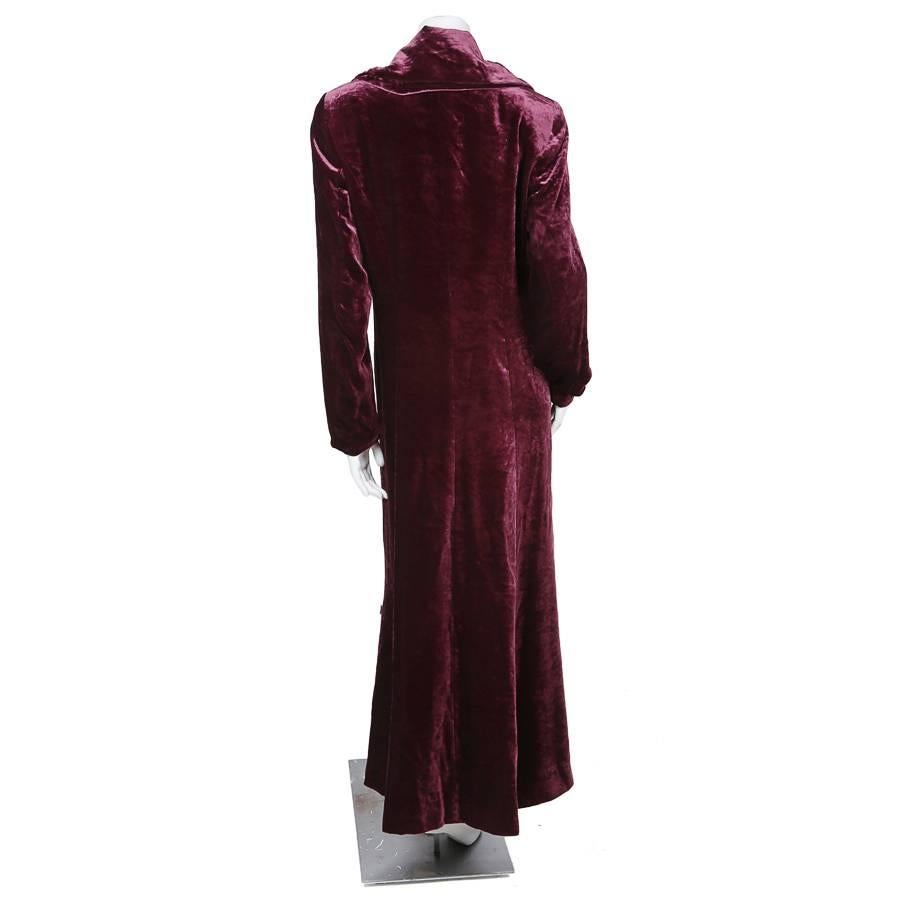 This is a long jacket by Kenzo circa 1980s.  It is made from a merlot colored velvet and features a large lapel and two hidden front pockets.  It is satin lined and closes by a single fuchsia button at the left waist.  The shoulder to shoulder