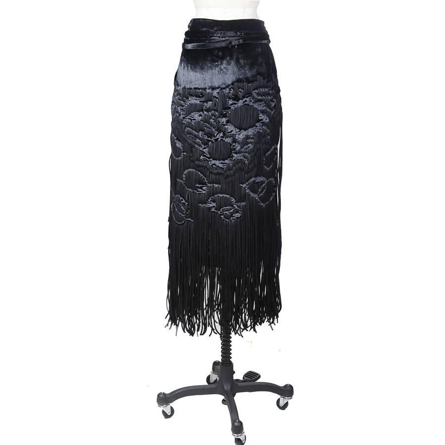 This is a fringe skirt by Tom Ford for Yves Saint Laurent c. 1990s.  There is a subtle textured pattern created by vertically weaving the fringe in and out of the velvet.  The back includes an attached cinch tie.  The closure is an invisible side