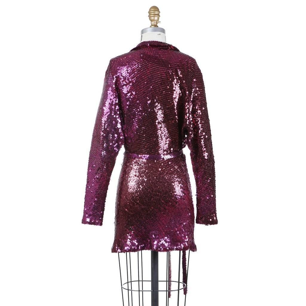 This is a dark fuchsia sequin shirt dress by Halston c. 1970s.  It features a plunging V neckline with a collar and long sleeves. It comes with a sequin belt.