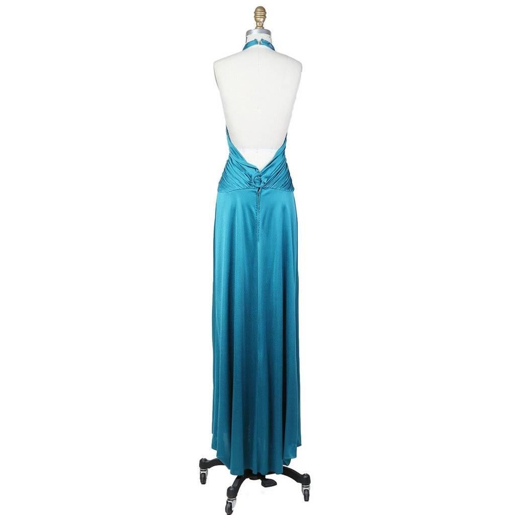 This is an aqua colored silk jersey dress by Loriz Azzaro c. 1970s.  It features a halter style neckline and ruching in the bodice and waist that holds together by a ring around the center of the waist.  The closure is a back zipper with hook and