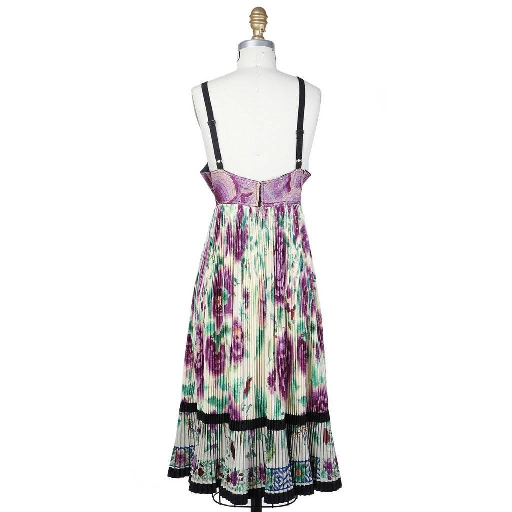 This is a Pleated Floral Cone Dress by Jean Paul Gaultier circa 1980s. It features a pleated skirt and built-in cone bra with stitch detailing. Closures include an invisible zipper and four hook-and-eyes. Materials: 65% Wool/35% Silk. 