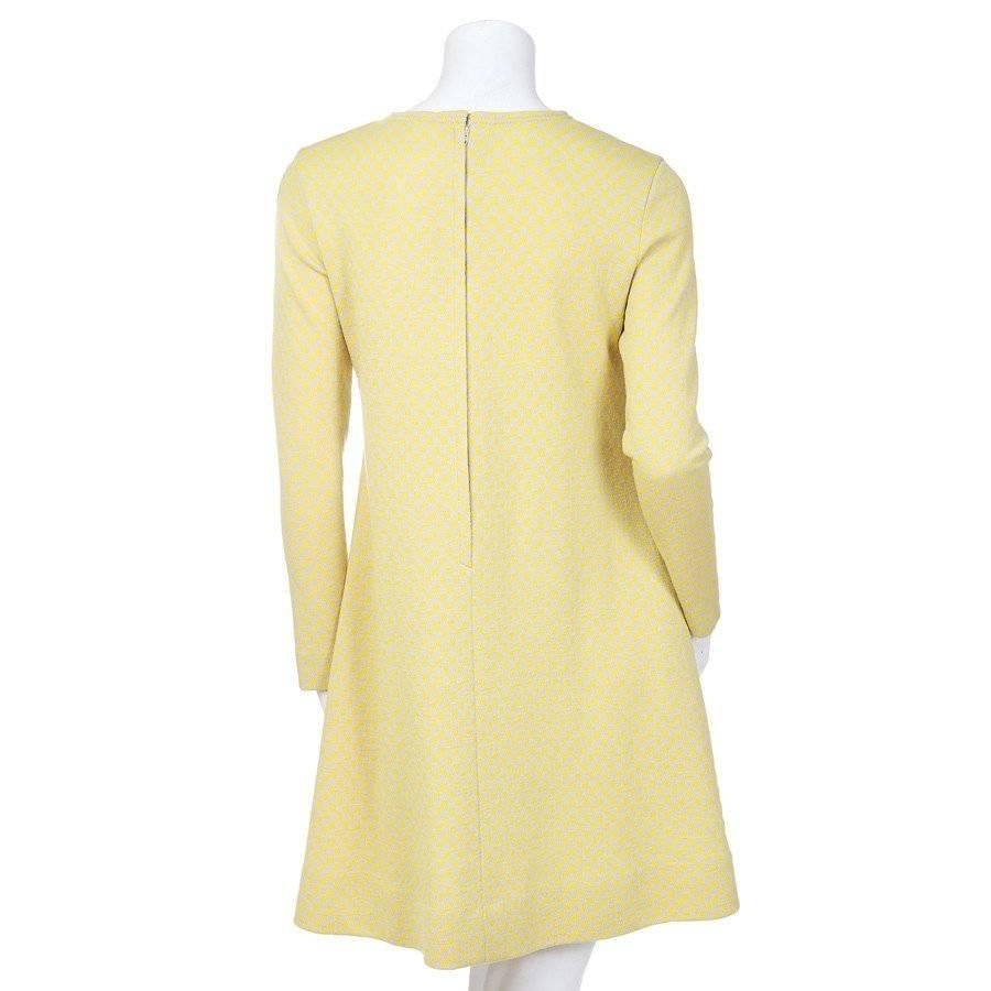 This is a checker print mini dress from Rudi Gernreich c. 1960s.  It features a short A line skirt, a high neckline, and long sleeves. The checker print consists of dandelion yellow and taupe colored squares.  It also features hip pockets hidden in
