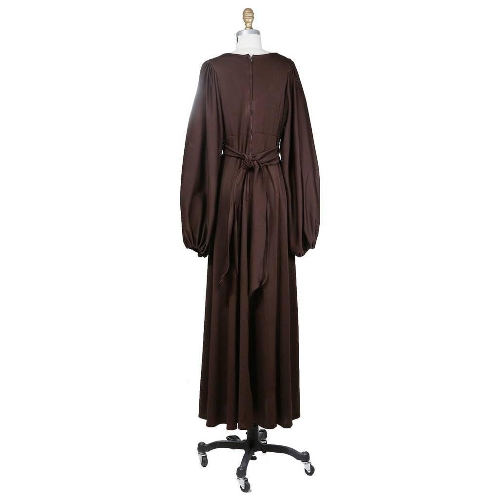 This is a brown jersey peasant dress by Ossie Clark circa 1970s. It has bishop style sleeves, a wrap around belt, and an arched empire waist.  The closure is an invisible zipper down the back.  