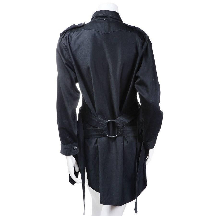 This is a shirt from 1976 by Vivienne Westwood for Malcolm McLaren.  It is a black pullover shirt with a button up polo style neckline and two shoulder tabs.  The jacket features adjustable bondage straps that are bound by two rings, one in the