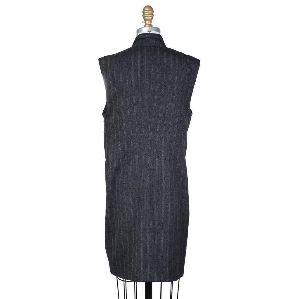 This is a menswear inspired sleeveless shift dress from Yohji Yamamoto c. 1990s.  It is made from a dark grey double pinstripe menswear fabric.  The front is a single breasted button closure in the style of a suit jacket.  It features a chest pocket