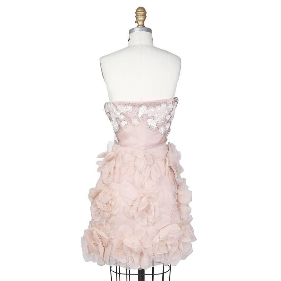 This is a contemporary cocktail dress by Valentino.  It is made from a blush pink silk with large scale organza flowers on the skirt.  Details include the white embroidery and silver jewel embellishment around the bust.  There is a silk lining and