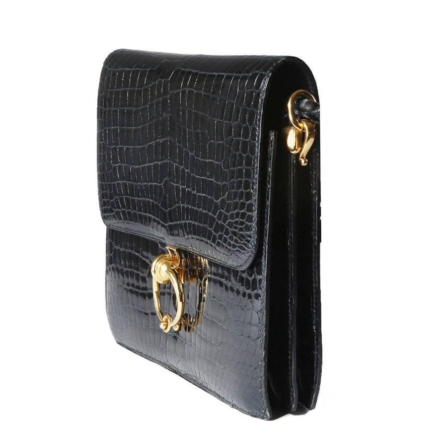 This is a black patent crocodile shoulder bag by Hermes from 1986.  It features a flap closure with a circular flip clasp.  The gold hook hardware on the side is also curved to add a decorative touch.  
Length is 8.5"
Width is 1.75"
Height