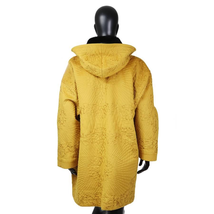 This is a mustard yellow wool oversized coat by Gianni Versace c. 1980s.  It features an embroidered design on the outside with a baroque patterned silk lining.  It has 4 outer pockets, 2 zip pockets on the chest and 2 hip pockets.  There is also 1