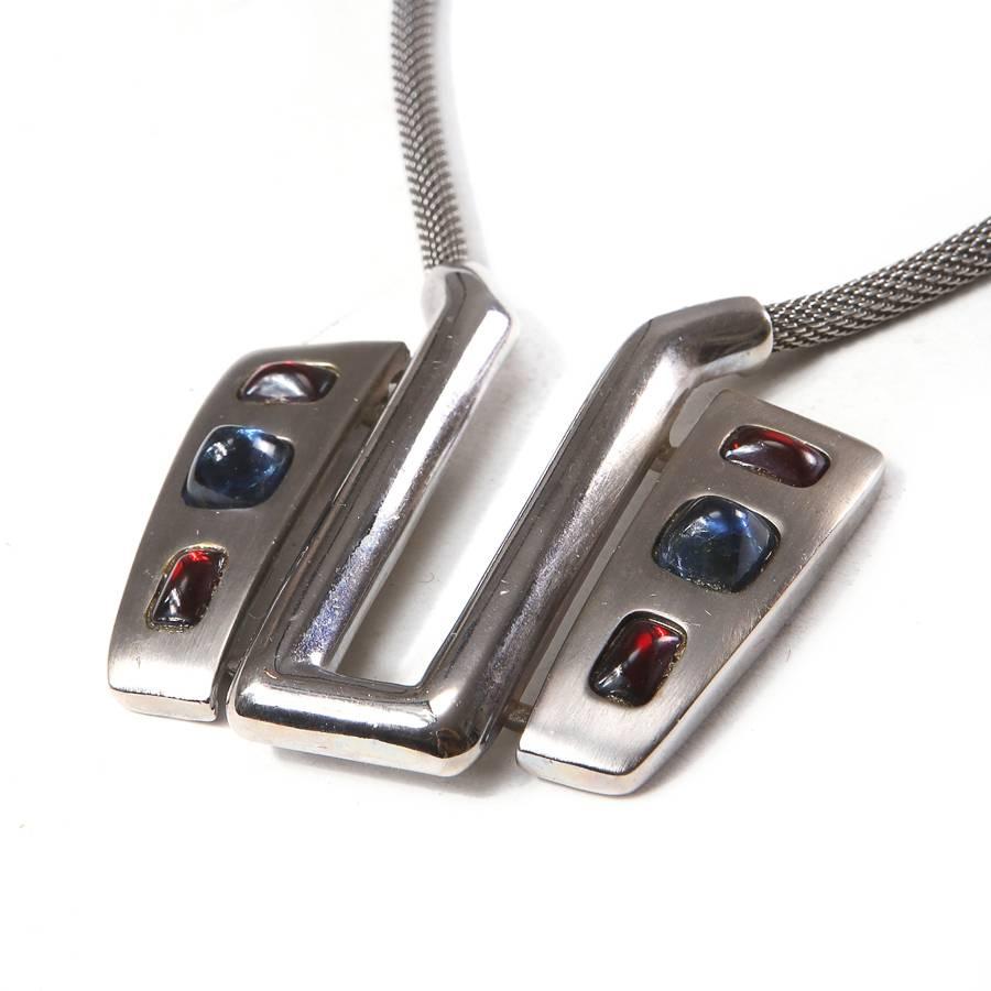 This is a pendant necklace by Pierre Cardin from the 1960s.  It features a U shape pendant with sapphire and ruby jewel stone inlays.  
The circumference is 16"
