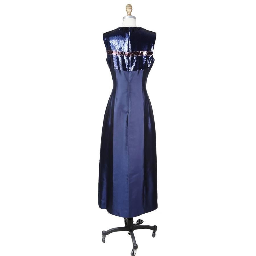 This is a navy blue sleeveless evening dress by Christian Dior.  It is made from a navy blue moire fabric and features a sequin and beaded design in the front and back of the top.  It has a princess cut and the closure is an invisible zipper down