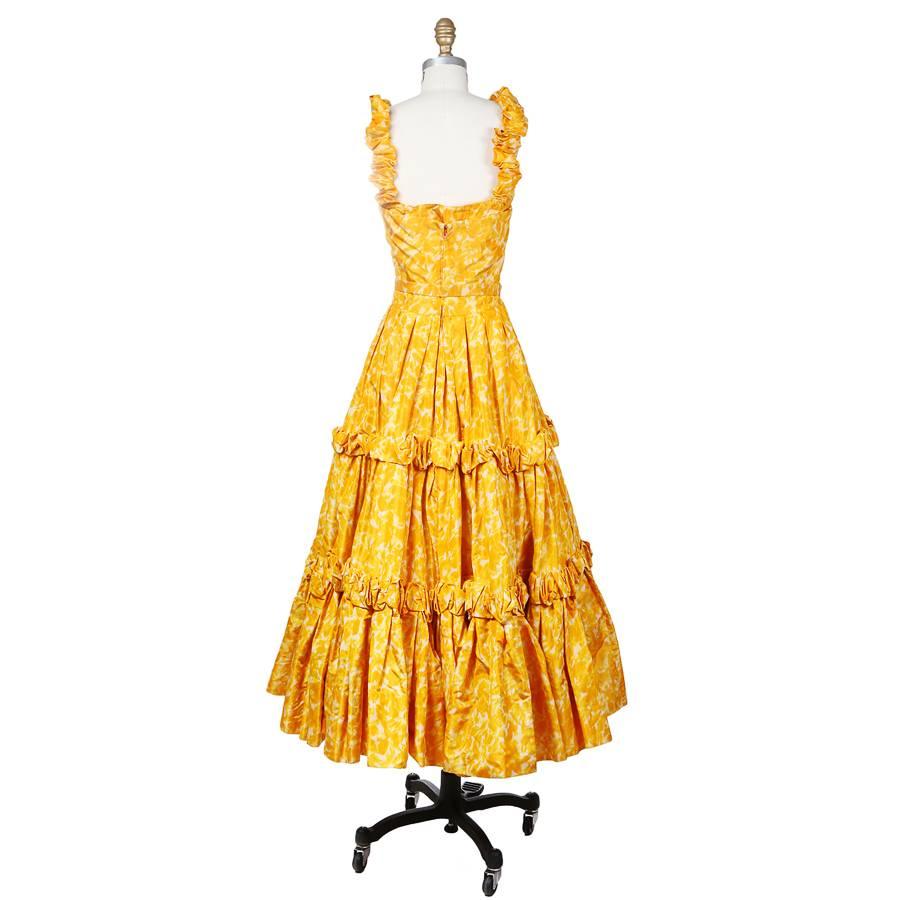 This is a classic circle skirt Dior dress from 1958 as stated by the tag inside.  It features ruched fabric straps, rosette rings around the skirt, and comes with a matching belt for the waist. The dress includes a structured inner lining and
