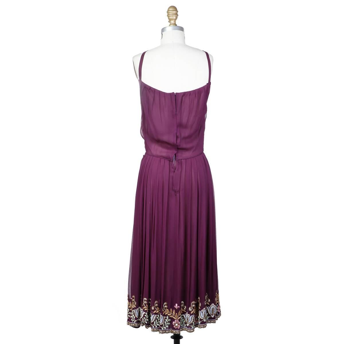 This is a halter dress by Christian Dior c. 1980s.  It is made from a purple chiffon and features a floral beaded and embroidered design along the bottom hem.  It includes an attached slip lining with a zipper and snap closures on the outside. 