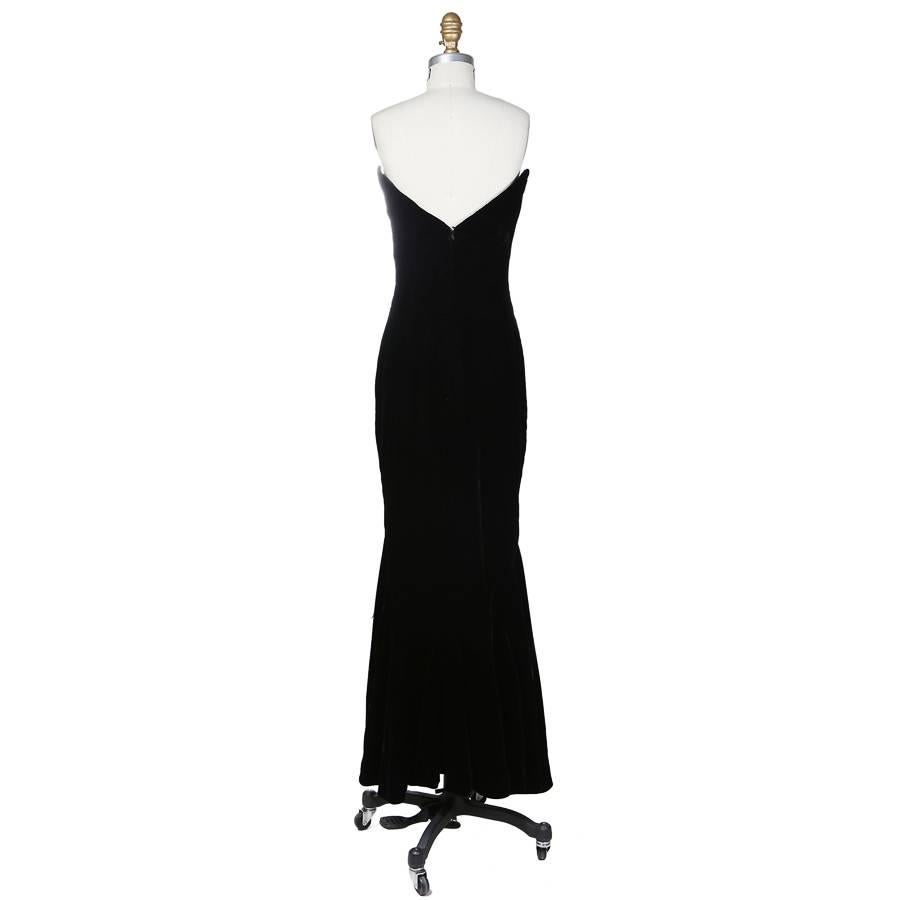 This is a strapless dress c. 1980s.  It is made of black velvet satin and features buttons down the center front. The dress is mermaid cut and includes an inner corset.  