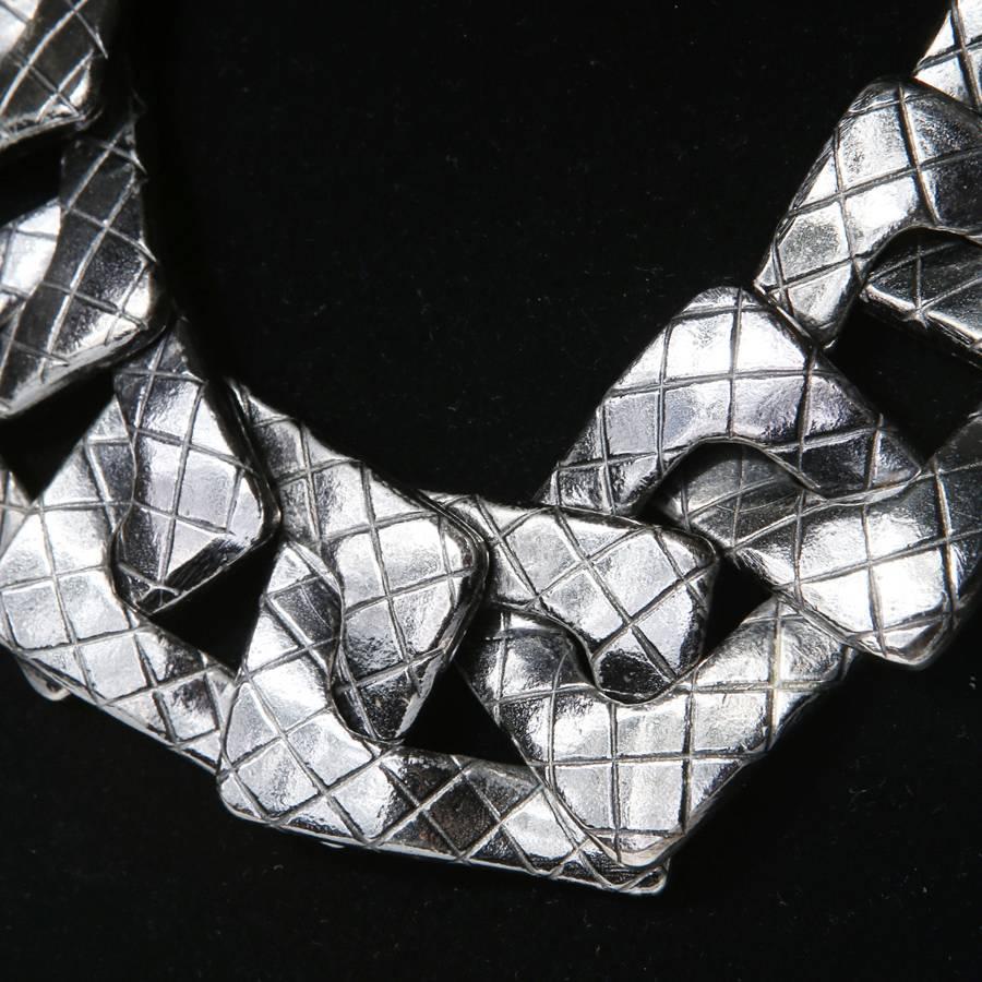 This is a necklace by YSL c. 1980s.  It features large square chain links with a criss cross pattern on them and double chain link in back.  The closure is a hook and ring.  