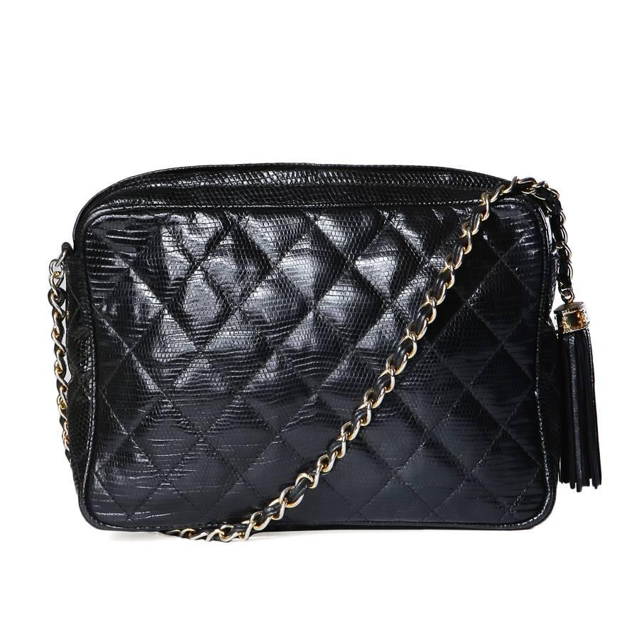 This is a shoulder bag by Chanel from 1986-1988.  It is made of black quilted lizard and features gold hardware, top zipper closure with a tassle, and an inside zipper pocket.  
8.75