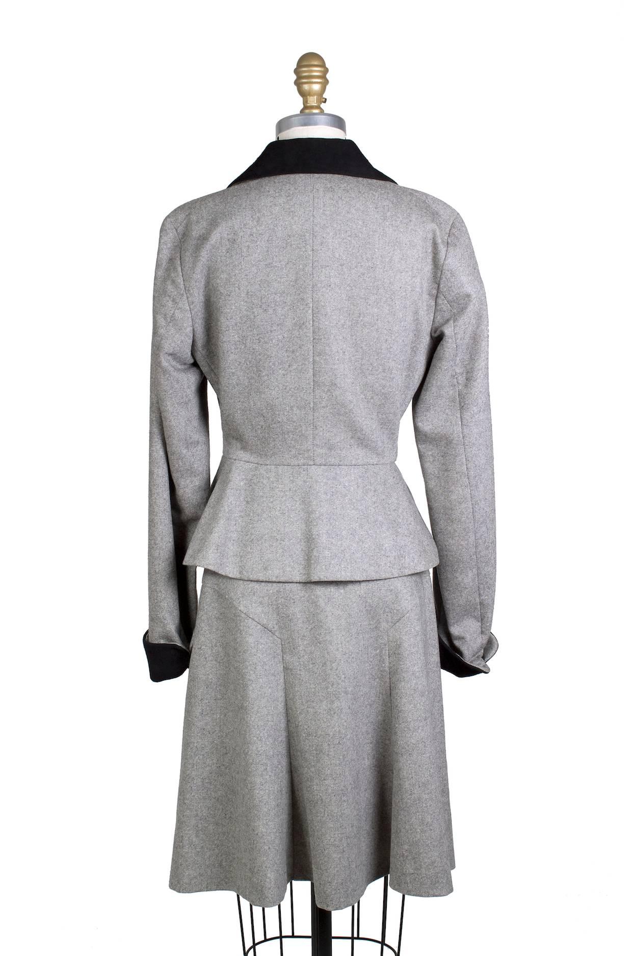 This is a skirt suit by Vivienne Westwood from recent.  It is made from grey wool with black cuffs and collar and features a belted jacket with button closure.  Zipper and button closure on skirt and both pieces are lined in a beige satin.

Skirt
