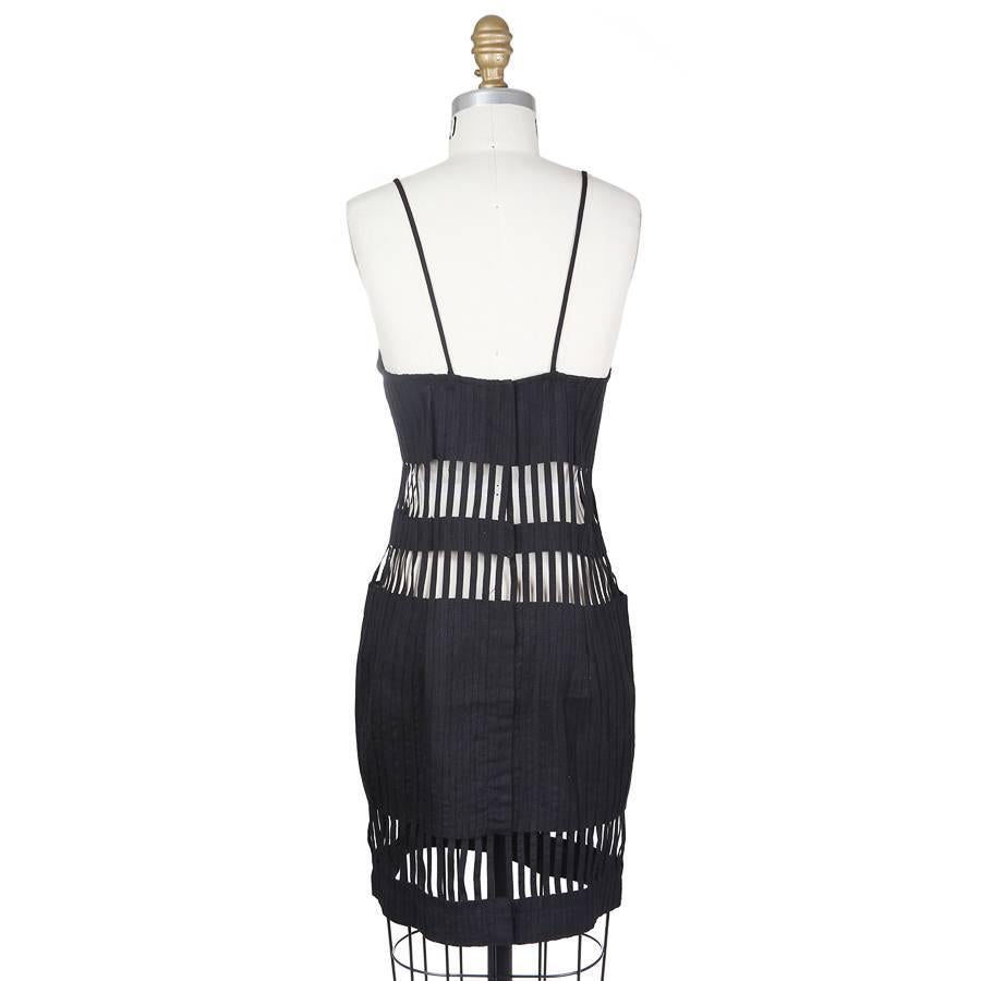 This is a black dress by Todd Oldham from Spring 1992.  It features vertical bar cut outs to create a cage effect around the dress. It has spaghetti straps and the closure is hidden hook and eye closures down the back.
